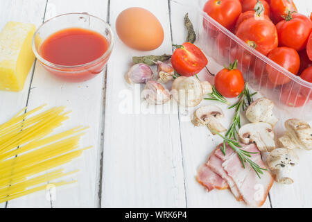 Frame with spaghetti and various ingredients for cooking pasta on a white background, top view. Stock Photo