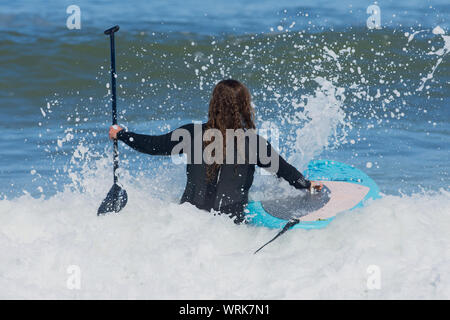 A surfer enters the ocean at Newcomb Hollow Beach, Wellfleet, Massachusetts on Cape Cod, USA Stock Photo