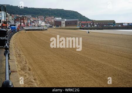 The sands in the south bay at Scarborough which have been cleaned with a tractor for the visitors that day with the lifeboat station in the background Stock Photo