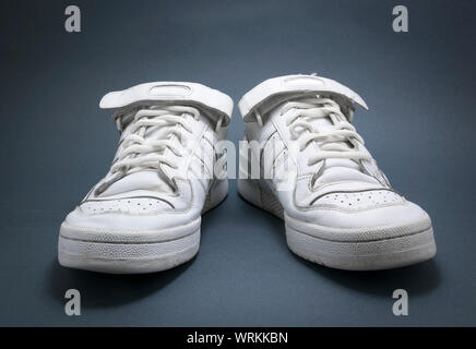 White basketball sneakers on blue background with black vignete. Stock Photo