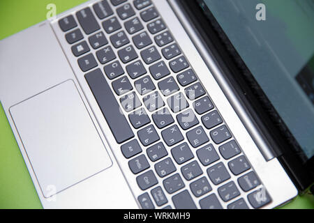 Modern laptop computer on green background. The concept of work in the office.Metal laptop keyboard small depth of field . Office work with notebook Stock Photo