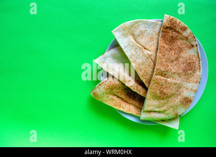 Famous traditional Arabic pita bread in white plate on green background. Flat lay, top view with copy space. Stock Photo