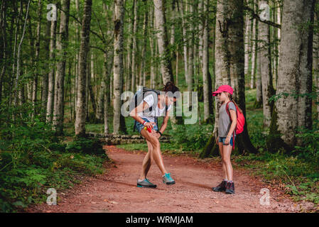 Mother and her daughter hiking in the forest and she applying mosquito repellent on the skin Stock Photo