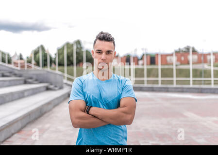 Athletic male athlete, standing in the summer in city, motivation for doing fitness sport workout, in the morning at a workout. Active lifestyle of Stock Photo