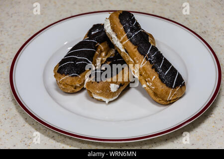 Freshly baked eclairs on a white plate Stock Photo