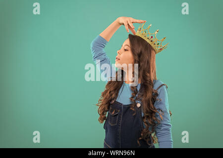 Feels like queen. Kid wear golden crown symbol of princess. Every girl dreaming to become princess. Lady little princess. Girl cute baby wear crown while stand blue background. Childhood concept. Stock Photo