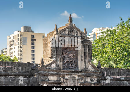 Manila, Philippines - March 5, 2019: Fort Santiago. Apartment buildings appear in blue sky behind top of Monumental main gate into the fortress with i Stock Photo