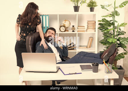 Offer massage. Man bearded hipster boss sit in leather armchair office interior. Boss and secretary girl at workplace. Relations at work. Business people and staff concept. Lazy boss office. Stock Photo