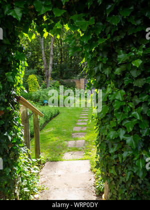 The Physic garden at Chenies Manor on a Summer evening. An Ivy keyhole leads the eye along the paved path into the walled herb garden. Stock Photo