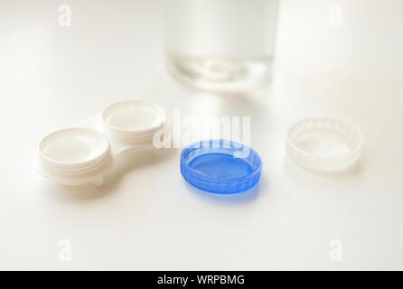 Accessories for the proper use of contact lenses: case, tweezers and bottle of solution on white background. Safe vision correction. Selective focus. Stock Photo