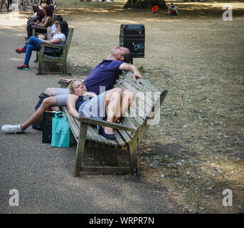 Two people napping on a park bench in St. James Park, Central London , on 25 July 2019 , England. (Photo by Ioannis Alexopoulos / Alamy) Stock Photo