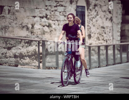 Cordoba, Spain - June 20, 2019: Two funny girls riding in bicycle Stock Photo