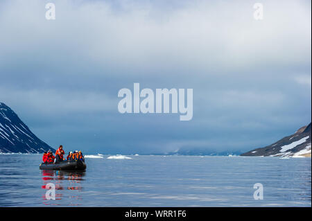 HORNSUND, SVALBARD, NORWAY – JULY 26, 2010: Tourists from the National Geographic Explorer cruise ship on inflatable rafts in the Artic Ocean exploring a fijord in the Arctic. Stock Photo