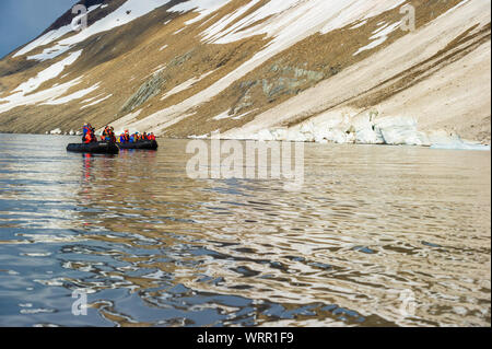 HORNSUND, SVALBARD, NORWAY – JULY 26, 2010: Tourists from the National Geographic Explorer cruise ship on inflatable rafts in the Artic Ocean exploring a fijord in the Arctic. Stock Photo