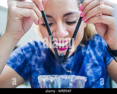 Happy Woman Picking Up Blueberry With Drinking Straws Over Glass