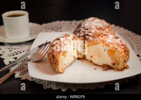 Choux cream or cream puff and coffee on dark background. Selective focus. Stock Photo