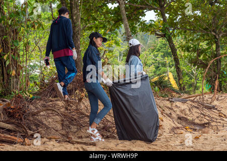 People of different nationalities cleaning garbage on the black beach to clean the beach in the world environment, volunteer concept Stock Photo