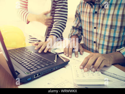 Two colleagues discussing data working with construction plan in office. Stock Photo