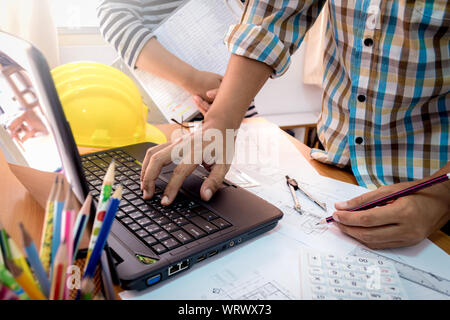 Architect with partner working with laptop on construction plan in office Stock Photo