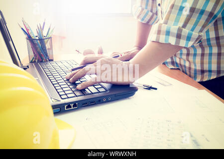 Architect working on laptop with construction plan in office Stock Photo