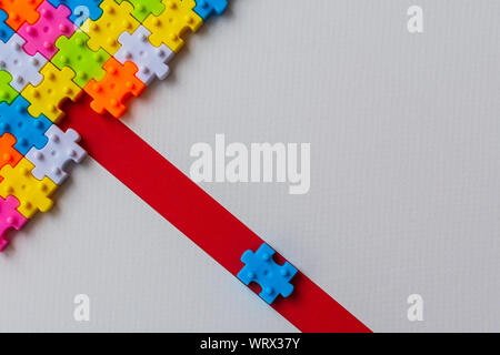 Colors plastic jigsaw puzzle on white paper background, Missing one jigsaw puzzle on red line to complete with copy space, Business strategy teamwork Stock Photo