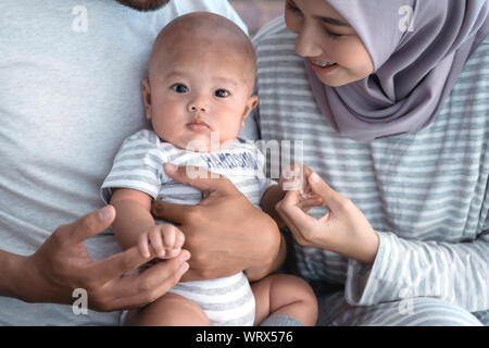 baby boy smiling while sitting on parent's lap Stock Photo