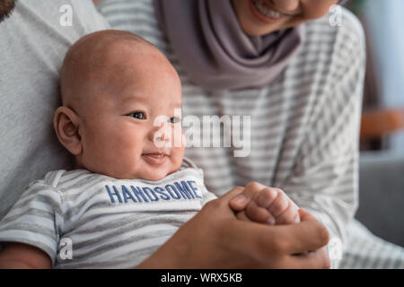 baby boy smiling while sitting on parent's lap Stock Photo