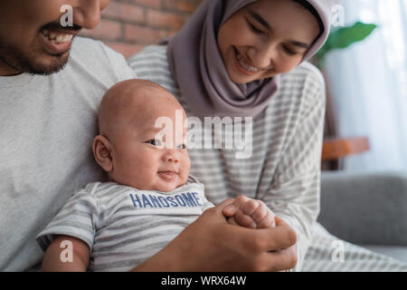 baby boy smiling while sitting on parent's lap Stock Photo