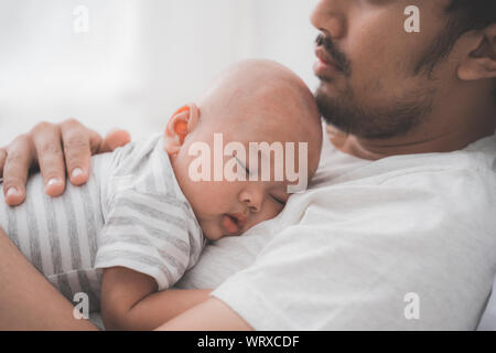 cute baby boy sleeping on father's chest Stock Photo