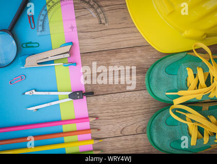 Sneakers, construction helmet, writing material and other on wooden plank, Education concept. Stock Photo