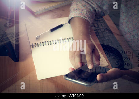 Hands of business woman touching smart phone screen. Double exposure finance accounting with money under shinning light Stock Photo