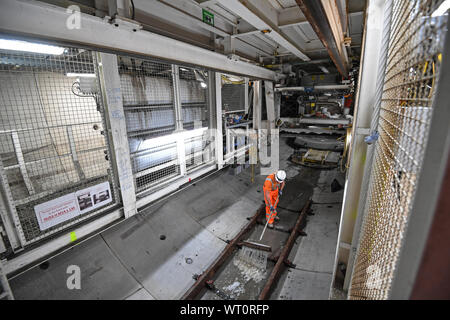 An engineer sweeps away waste water inside a Boring machine excavating a section of the Thames Tideway Tunnel in London. Stock Photo