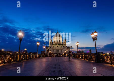 Illuminated Cathedral of Christ the Savior framed with old style street lights of Patriarchy Bridge at night. Stock Photo