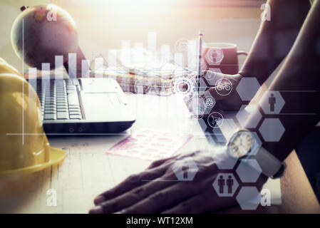 Hands of architect drawing construction plan on office desk with virtual graphic icon diagram. Stock Photo