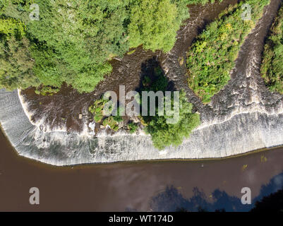 Aerial photo of a small waterfall with bright green trees around it taken in British town of Leeds in West Yorkshire Stock Photo