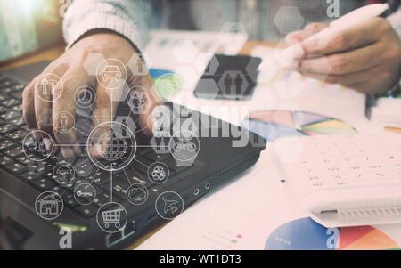 Businessman working on laptop with marketing information graph  and virtual graphic icon diagram. Stock Photo