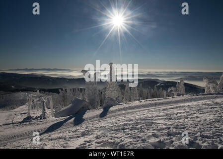 spectacular view with many mountain ranges, sun with clear sky and fog in valleys from Lysa hora hill in winter Moravskoslezske Beskydy mountains in C