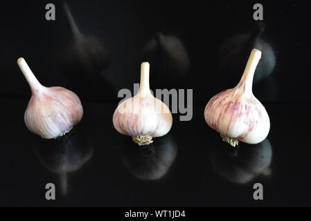Fresh vegetables, three heads of a calf lying on a black glossy surface with repeated reflection. Stock Photo