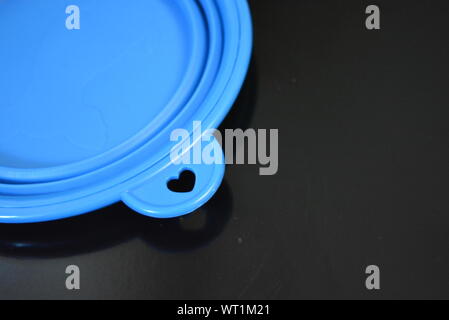 Blue folding and multifunctional rubber plate, a bowl with a plastic edging on a black glossy surface. Stock Photo