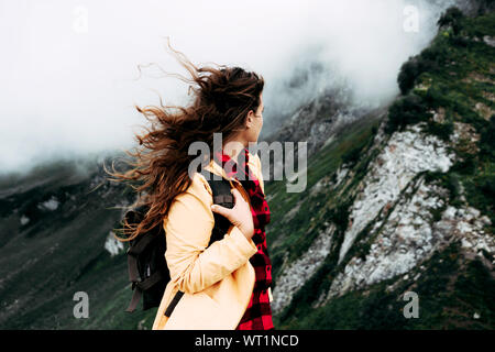 girl with long curly hair in the mountains view from the back Stock Photo