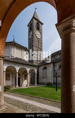 The beautiful baptistery and the bell tower of Baveno, Italy, framed by the columns of the portico of the via crucis, in the monumental complex Stock Photo