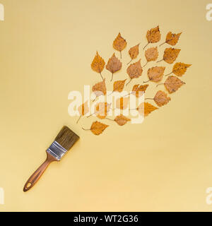 Autumn concept, flat lay composition. Brush and autumn leaves on a yellow background. Top view. Stock Photo