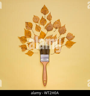 Autumn concept, flat lay composition. Brush and autumn leaves on a yellow background. Top view. Stock Photo