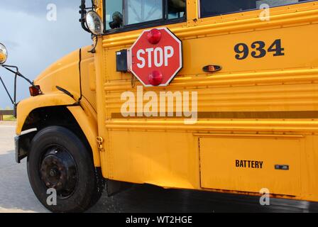 Yellow school bus with visible stop sign in rainy weather Stock Photo