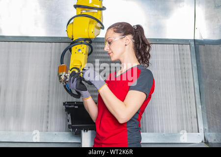A young female technician while machine constructing in a manufacturing plant Stock Photo