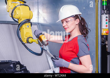A young female technician while machine constructing in a manufacturing plant Stock Photo
