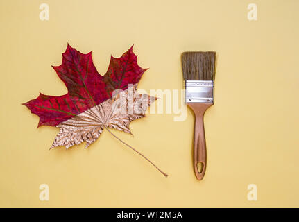 Brush and maple leaf on a yellow background. Autumn concept, flat lay. Top view. Stock Photo