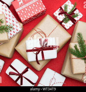 Christmas gift box wrapped in ornament paper and decorative red rope ribbon on red surface. Creative hobby, top view. Prepare to Xmas. Banner. Stock Photo