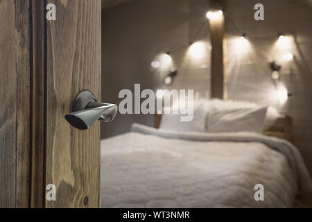 Opened wooden door to blurred bedroom with house interior as background. Abstract background for design. Stock Photo