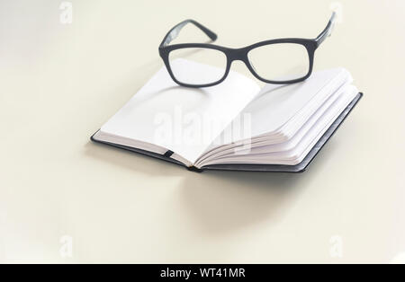 a pair of eyeglasses on an open notebook with blank pages. Office and study. Pages yet to be written Stock Photo